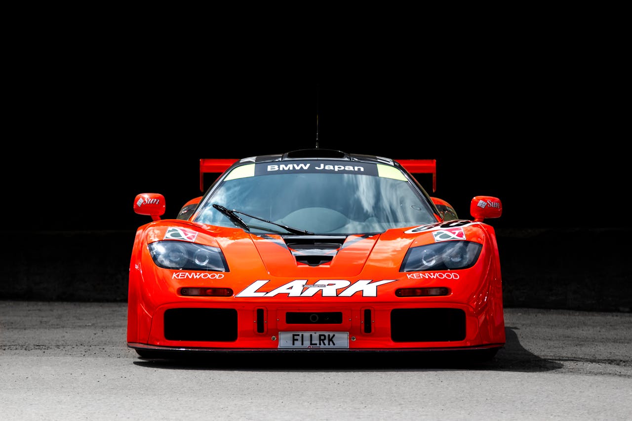 Front view of a vibrant red McLaren F1 racing car with bold branding, showcasing a sleek design.